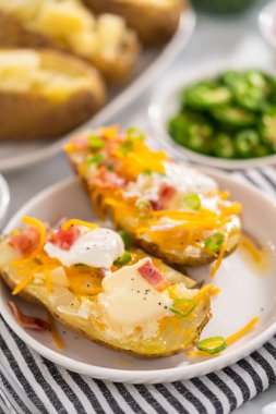 Fırında pişmiş patates. Tereyağı, ekşi krema, peynir ve pastırma parçalarıyla süslenmiş büyük fırında patates..