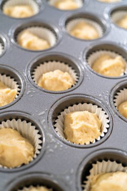 Scooping cupcake batter with dough scoop into a baking pan with liners to bake American flag mini cupcakes.