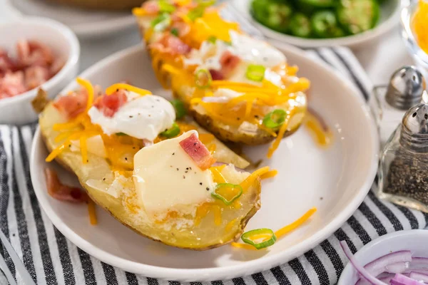 Pressure Cooker Baked Potatoes. Garnished large baked potatoes with butter, sour cream, cheese, and bacon bits on a white plate.