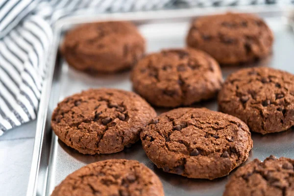 Freshly baked double chocolate chip cookies on a baking sheet.