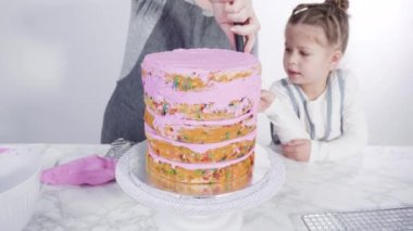 Adım adım. Pembe tereyağlı krema kaplı yuvarlak funfetti kek katmanları.