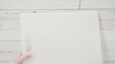 Düz yatıyordu. Adım adım. Beyaz kesim tahtasında ev yapımı macadamia şekerlemesi kesiyorum..