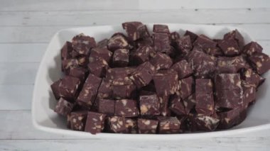 Adım adım. Beyaz servis tabağında küçük küplere kesilmiş Macadamia şekerlemesi..