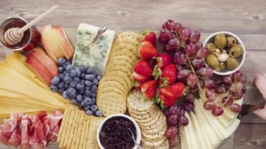 Düz yatıyordu. Aperatif olarak sunulan tahtanın üzerinde gurme peyniri, kraker ve meyve var..