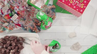 Düz yatıyordu. Adım adım. Ev yapımı macadamia şekerlemesi küçük hediye paketlerine konuyor..
