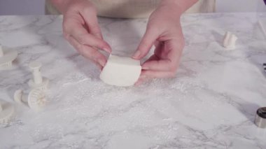 Adım adım. Mermer tezgahın üzerindeki beyaz fondanla kar tanelerini keserek..