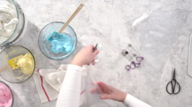 Düz yatıyordu. Adım adım. Tek boynuzlu at meringue kurabiyesi pişirmek için metal uçlu boru torbalarına krema karıştırılıyor..