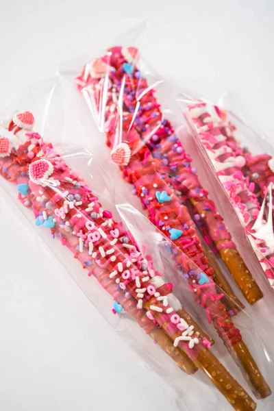 チョコレートで覆われたプレッツェルロッドは 明確な袋に詰められたバレンタインデーのためのハート型のスプリンクルで飾られています — ストック写真