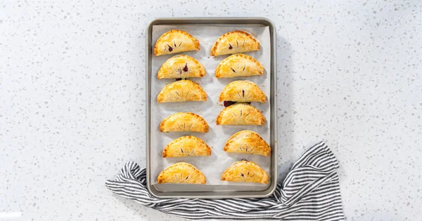 Flat lay. Freshly baked sweet empanadas with blueberries on the kitchen counter.