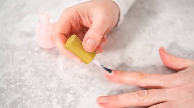 Kadın manikürünü evde basit manikür aletleriyle bitiriyor. Taze ojeyle oje sürüyorum..