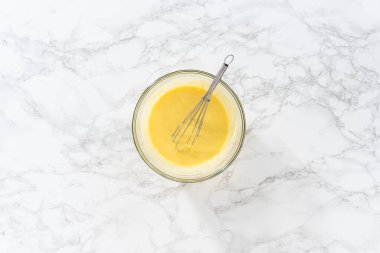 Küçük Paskalya ekmeği pişirmek için ıslak malzemeleri büyük bir bardakta karıştırıyorum..