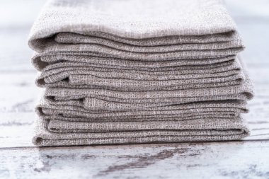 Ahşap beyaz bir masada doğal renkte keten bir peçetenin yakın görüntüsü..