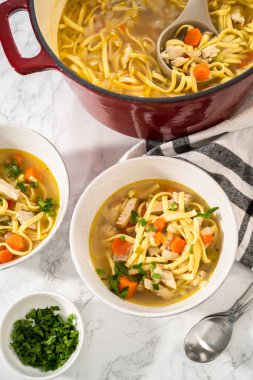 Beyaz seramik çorba kaselerinde kluski şehriyeli tavuk çorbası servis ediyorum..