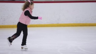 Küçük kız buz pistinde artistik patinaj yapıyor..