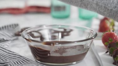 Adım adım. Çikolata kaplı çilek hazırlamak için organik çilekleri erimiş çikolatayla bir kaseye daldırmak..