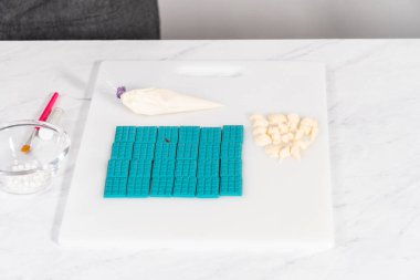 Çiseleyen beyaz çikolata ve üzerine beyaz inci şekeri serpiştiren mini çikolata ozanı.