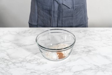 Yumuşak yulaf ezmesi üzümlü cevizli kurabiye pişirmek için büyük bir bardakta kuru malzemeler karıştırıyorum..