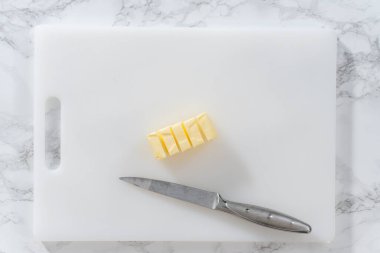 Düz yatıyordu. Beyaz bir kesme tahtasının üzerinde tuzsuz tereyağı dilimlemek.