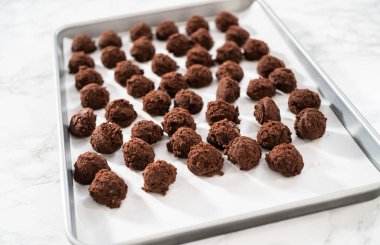 Naneli beyaz çikolatalı kurabiyeler pişirmek için parşömen kağıdıyla kaplı küçük bir hamur kepçesiyle kurabiye hamuru pişirmek..