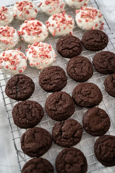 Dipping chocolate cookies into the melted white chocolate to prepare peppermint white chocolate cookies.