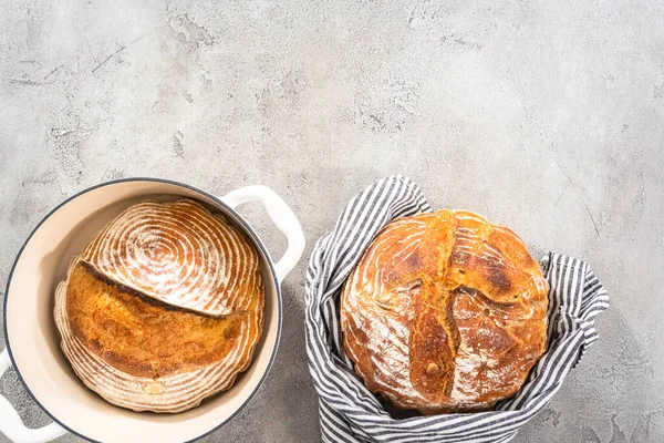 Flat lay. Freshly baked loaf of a wheat sourdough bread with marks from bread proofing basket in enameled cast iron dutch oven.