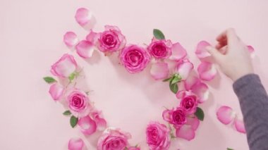 Düz yatıyordu. Pembe güllerden yapılmış kalp şekli ve pembe arka planda gül yaprakları..