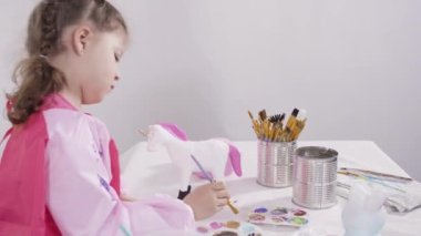 Küçük kız evde eğitim projesi için akrilik boyayla heykelcikler boyuyor..