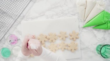 Düz yatıyordu. Adım adım. Buzlu kar tanesi şekilli şekerli kurabiyeler ve pembe krema..