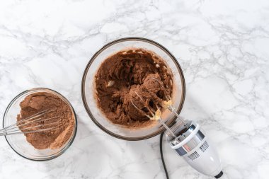 Flat lay. Mixing ingredients with a hand mixer to bake chocolate cookies with chocolate hearts for Valentines Day.