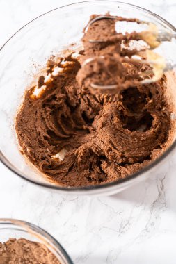 Mixing ingredients with a hand mixer to bake chocolate cookies with chocolate hearts for Valentines Day.
