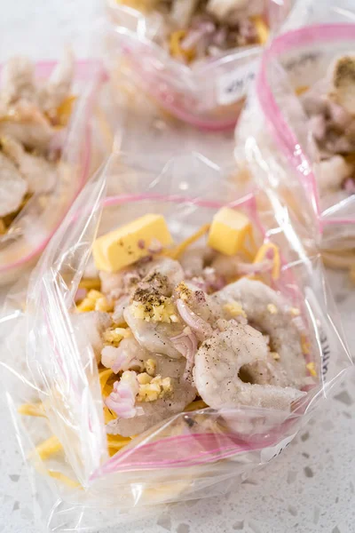 Packaging homemade frozen shrimp scampi meal prep into plastic resealable bags.