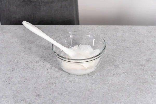 Mixing ingredients in a glass mixing bowl to prepare the white glaze.