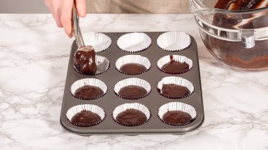 Step by step. Baking chocolate cupcakes. Scooping chocolate cupcake batter into a cupcake pan.