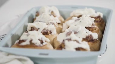 Taze pişmiş tarçınlı çörekleri mavi bir tavada jölelemek.