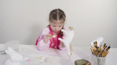 Evde resim dersinde kağıt heykel boyayan küçük bir kız..