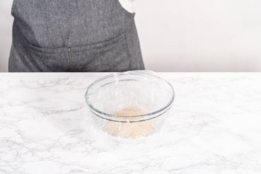 Tarçınlı tatlı pizzası hazırlamak için cam bir kasede pizza hamuru yetiştiriyorum..