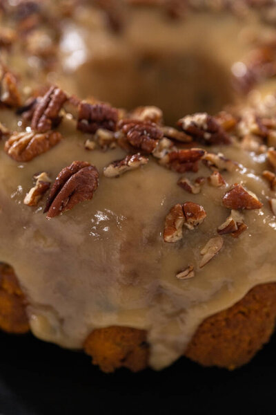 Freshly baked chocolate pumpkin bundt cake with toffee glaze topped with toasted pecans.
