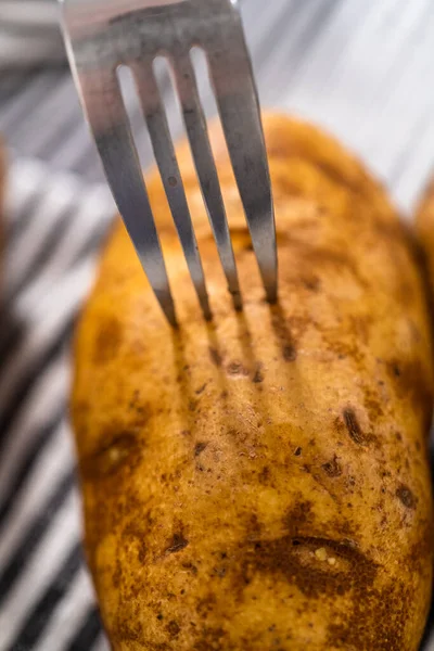 Pressure Cooker Baked Potatoes. Poking raw potatoes with a fork to prepare baked potatoes.