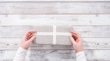 Adım adım. Ahşap beyaz bir masada doğal renkte keten peçete katlıyorum..