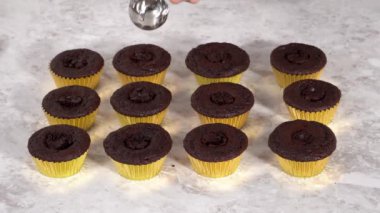 Çikolatalı kekleri tereyağlı krema ve gökkuşağı şekeriyle süslüyorum..