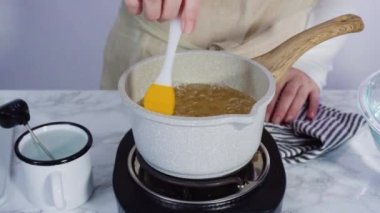 Adım adım. Küçük elektrikli ocağın üzerinde küçük bir tencerede karamelize şeker.