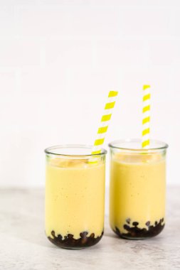 Taze yapılmış mango boba smoothie. Kağıt kamışla içme bardağında..