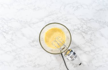 Düz yatıyordu. Mini vanilyalı kekler ve ombre pembe kremalı krema pişirmek için büyük bir karıştırma kabında malzemeler karıştırılıyor..