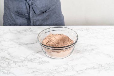 Büyük bir bardakta ıslak malzemeler karıştırarak kırmızı kadife kekler ve beyaz çikolatalı ganache kreması pişiriyorum..