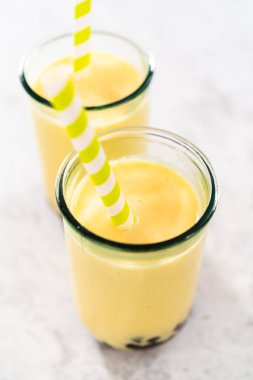 Taze yapılmış mango boba smoothie. Kağıt kamışla içme bardağında..