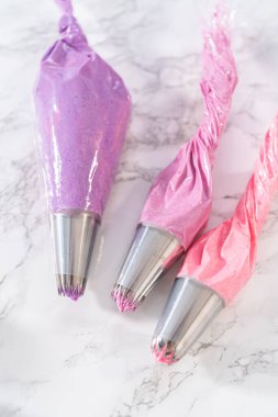 Mini vanilyalı keklerin üzerine pembe tereyağlı krema sıkıyorum..