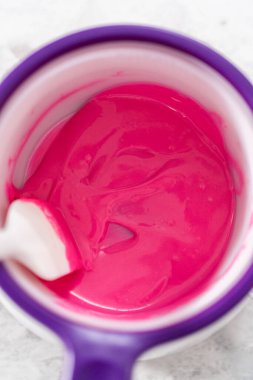 Çikolata erir, şeker tenceresinde erir. Gurme mini çikolatalar hazırlamak için çikolata serpiştirir..