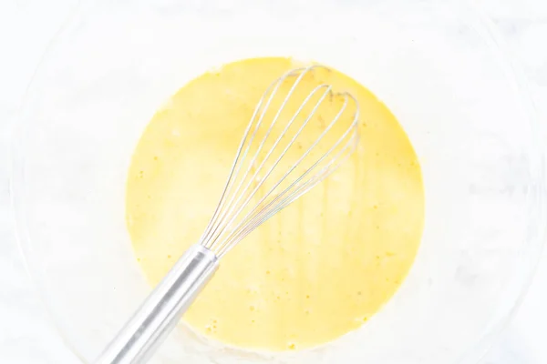 Mixing ingredients in a glass mixing bowl for spinach and ham frittata.