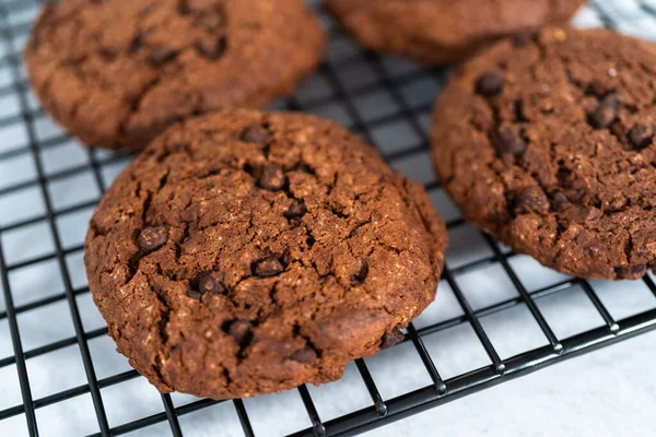 Freshly baked double chocolate chip cookies on a cooling rack.