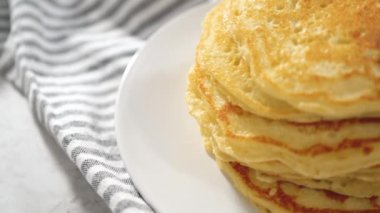 Dilimlenmiş muz, kızarmış hindistan cevizi ve akçaağaç şurubuyla süslenmiş taze hindistan cevizli krep yığını..